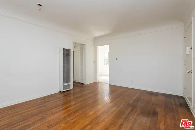 a view of an empty room with wooden floor and closet