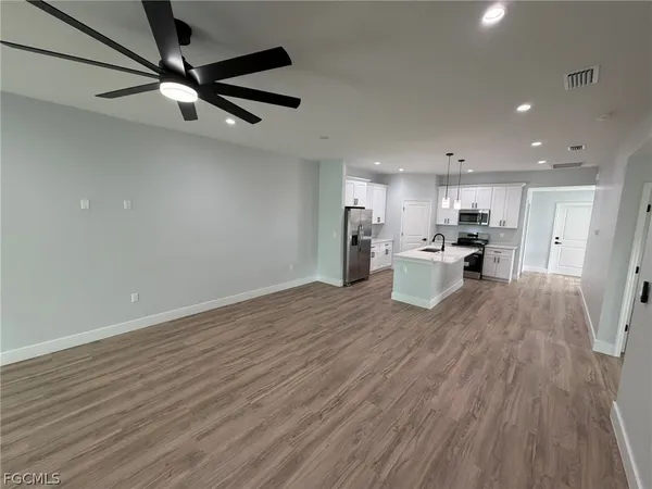 a view of a kitchen with a refrigerator a ceiling fan and wooden floor