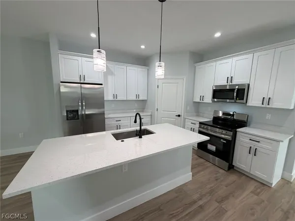 a kitchen with kitchen island a sink stainless steel appliances and wooden floor