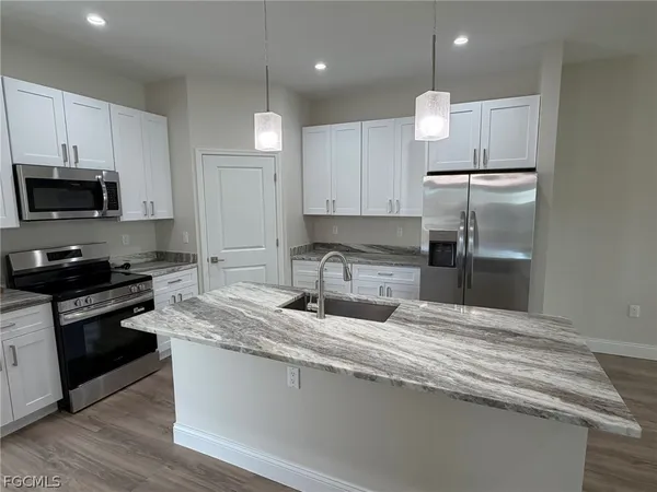 a kitchen with kitchen island granite countertop a stove a sink and a refrigerator