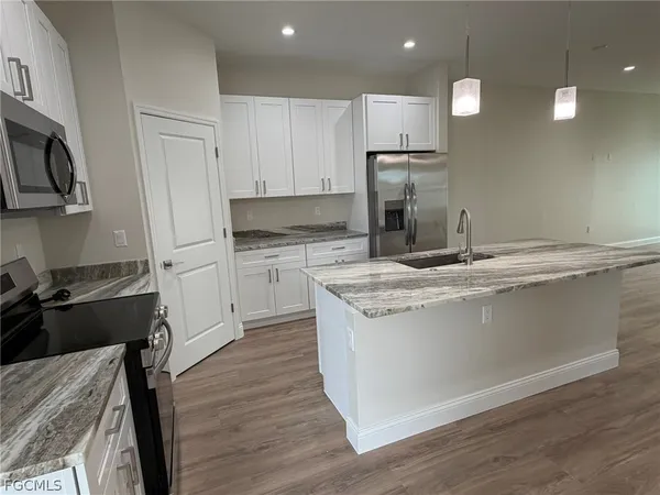 a kitchen with kitchen island a counter space a sink appliances and cabinets