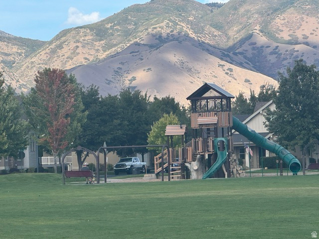 2029 West Crescent Row Mapleton, UT 84664 - Photo 28 of 28 Expansive green space featuring a playground with slides and a swing set, all set against a backdrop of mountains