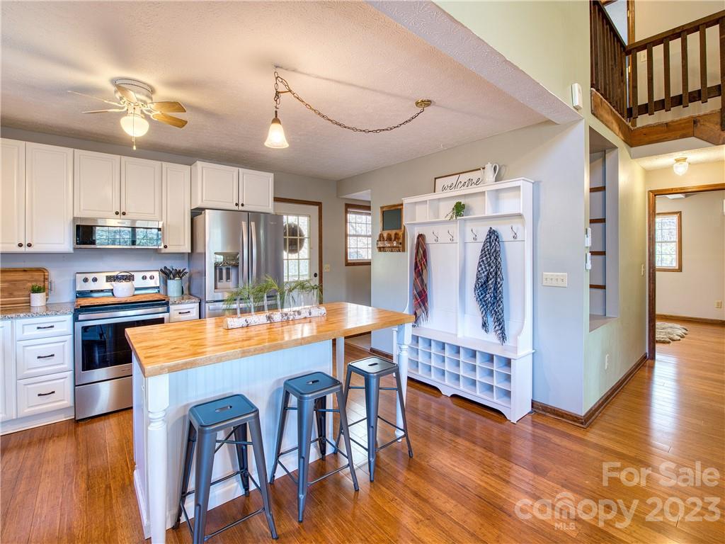 353 Rustic Heights Road Waynesville, NC 28785 - Photo 4 of 46 a kitchen with stainless steel appliances granite countertop a refrigerator a stove top oven a sink dishwasher and white cabinets with wooden floor