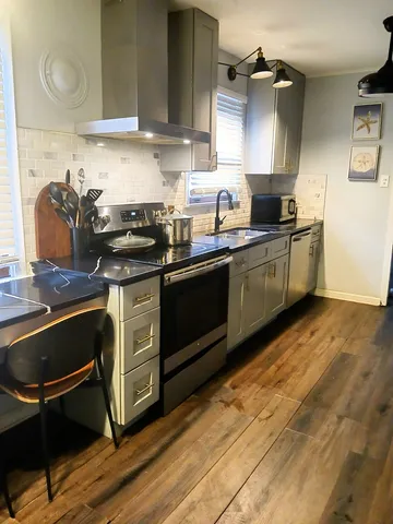 a kitchen with granite countertop a sink cabinets and stainless steel appliances
