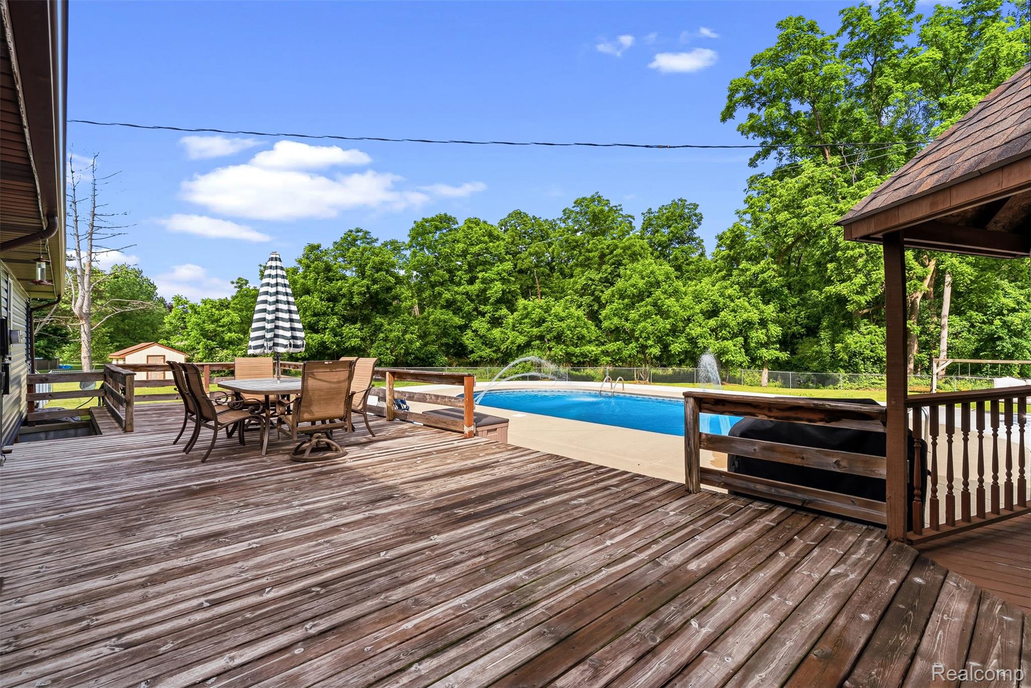 6699 Lansing Road Durand, MI 48429 - Photo 41 of 53 Expansive wood deck with pool access, featuring a built-in gazebo and wooden railings