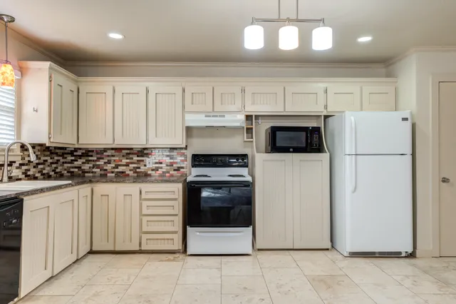 a kitchen with granite countertop a refrigerator and a stove top oven