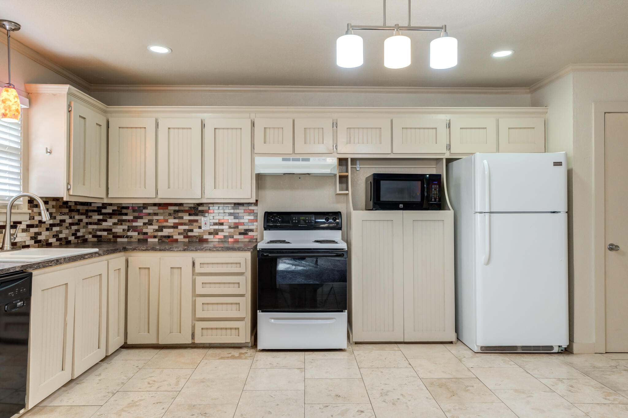 3517 47th Street Lubbock, TX 79413 - Photo 10 of 36 a kitchen with granite countertop a refrigerator and a stove top oven