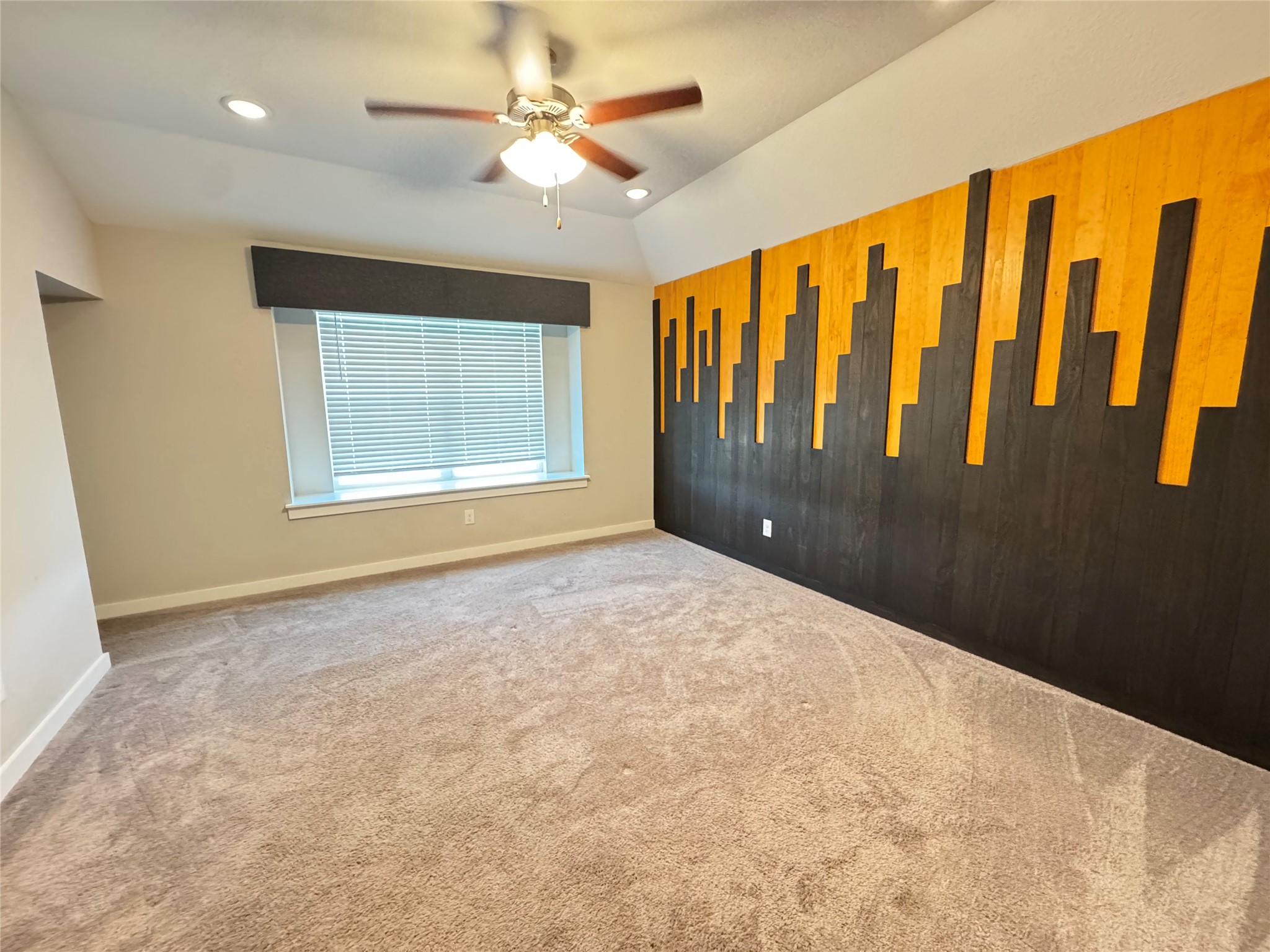 2328 Calvert Drive Leander, TX 78641 - Photo 20 of 35 Spacious room featuring a striking accent wall with black and wood-tone panels, vaulted ceiling, recessed lighting, ceiling fan, and carpet flooring