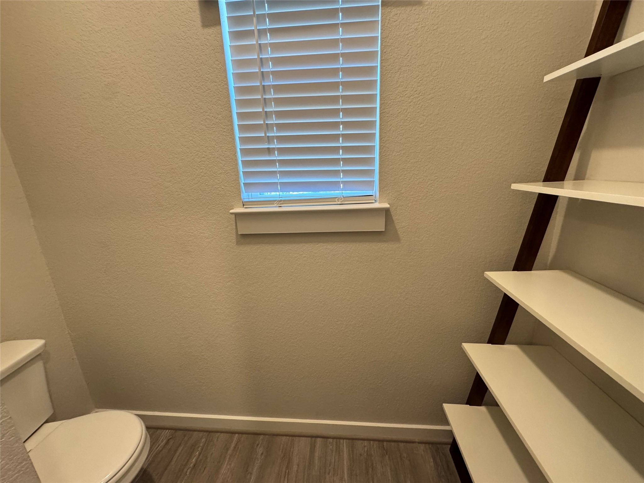 2328 Calvert Drive Leander, TX 78641 - Photo 25 of 35 Powder room featuring wood-finish flooring, a contemporary window with blinds, and a built-in ladder-style shelving unit