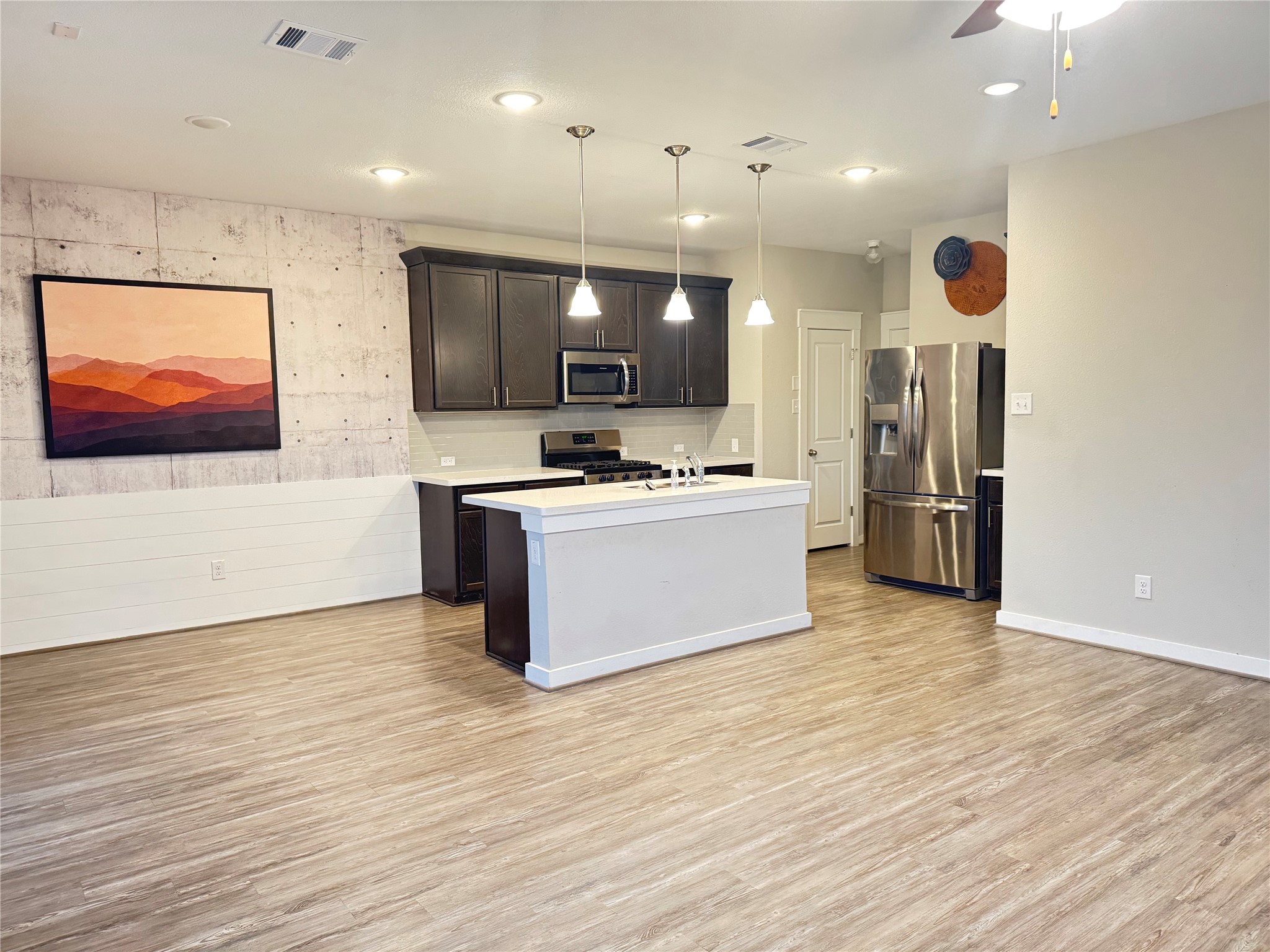 2328 Calvert Drive Leander, TX 78641 - Photo 5 of 17 a large kitchen with stainless steel appliances kitchen island a large counter top and a wooden floor