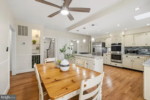 a kitchen with stainless steel appliances kitchen island granite countertop a dining table chairs and refrigerator