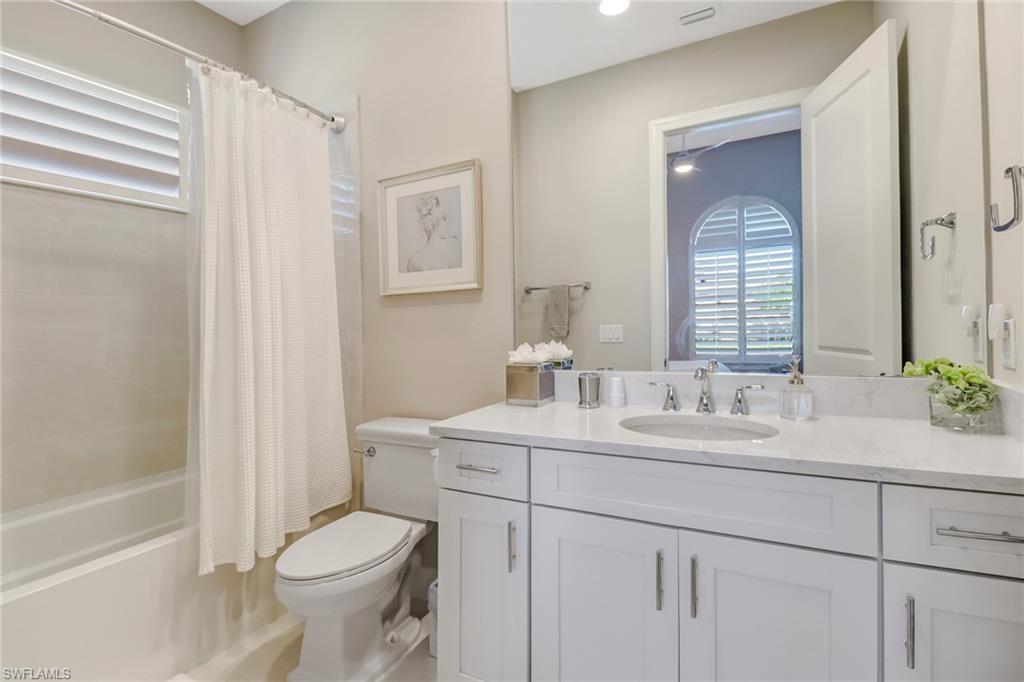 9412 Rapallo Street Naples, FL 34119 - Photo 26 of 34 a bathroom with a toilet sink and mirror