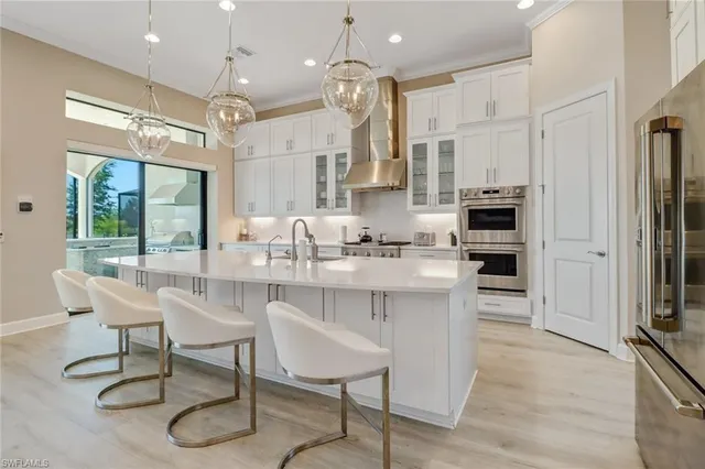 a kitchen with stainless steel appliances kitchen island granite countertop a table chairs and a refrigerator