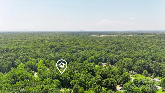 an aerial view of residential house with outdoor space and trees all around