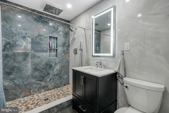 a bathroom with a sink vanity mirror and toilet