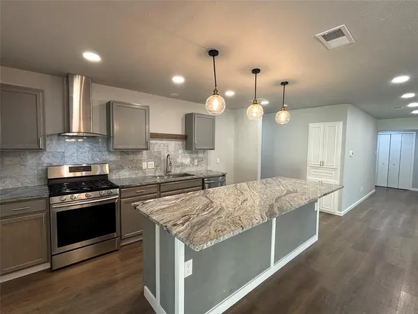 a kitchen with stainless steel appliances granite countertop wooden cabinets and a stove