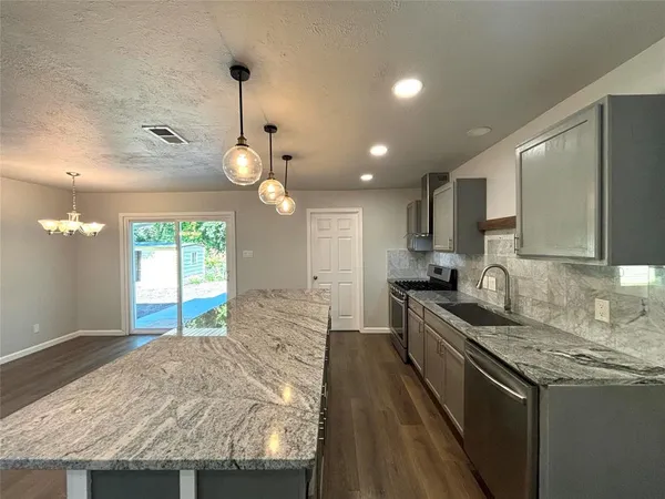 a kitchen with granite countertop a stove a sink a refrigerator and a granite counter tops