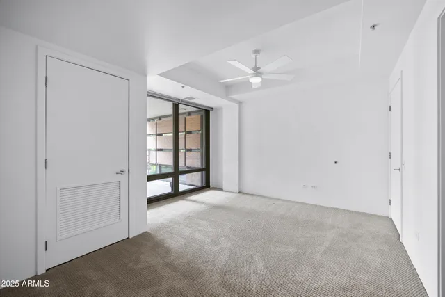 an empty room with windows and fan
