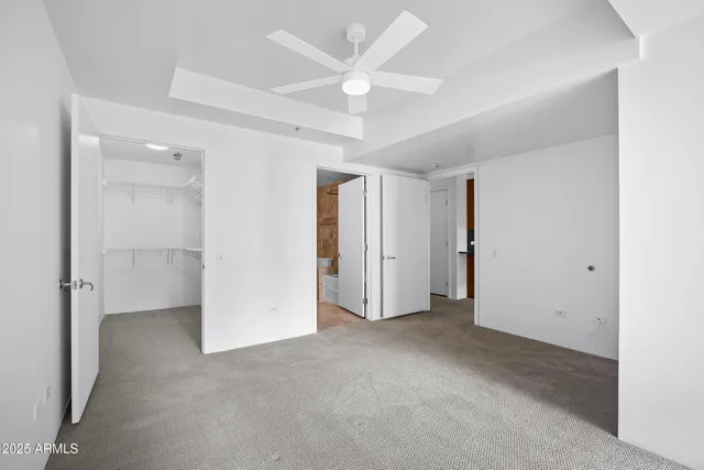 an empty room with closet and ceiling fan
