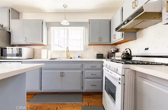 a kitchen with granite countertop a sink cabinets stainless steel appliances and a window
