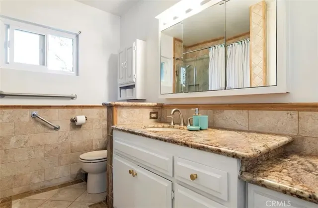 a bathroom with a granite countertop toilet sink and mirror