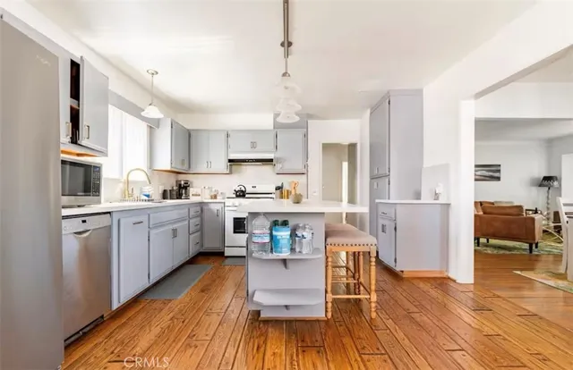 a kitchen with stainless steel appliances granite countertop a refrigerator a stove top oven and a dining table with wooden floor