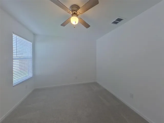an empty room with a window and a fan