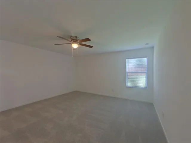 an empty room with a window and a ceiling fan