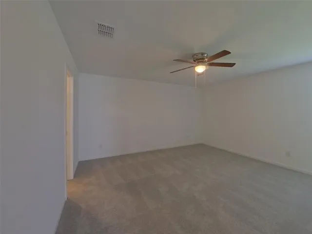 an empty room with a fan & a window