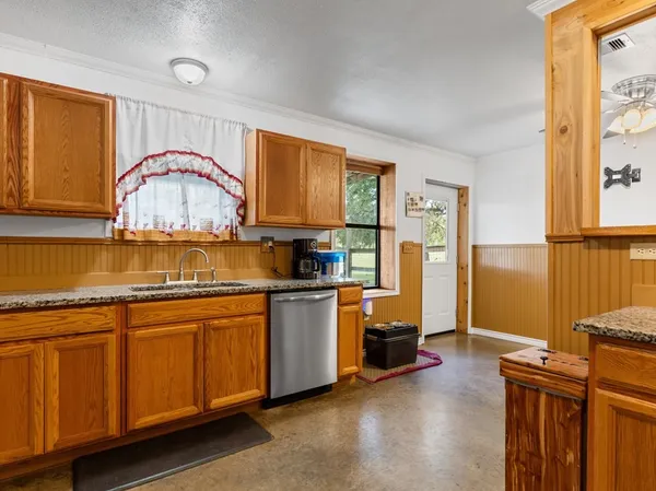 a kitchen with stainless steel appliances granite countertop a stove a sink dishwasher and a refrigerator with wooden floor