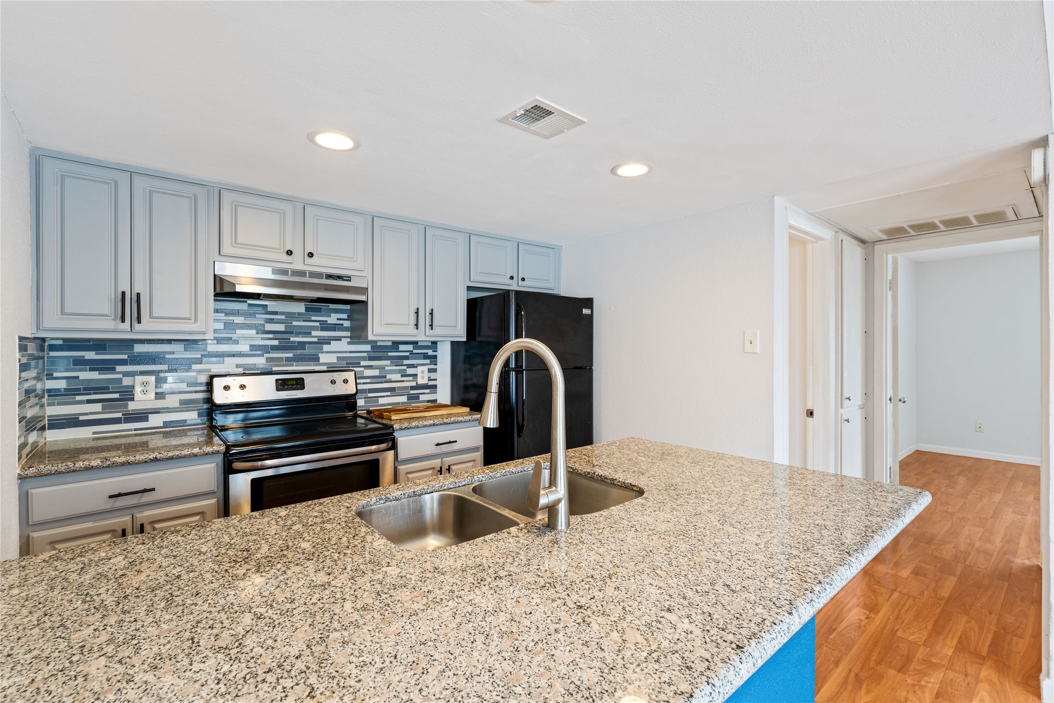 2124 Burton Drive, Unit 159 Austin, TX 78741 - Photo 11 of 23 A well-lit kitchen with granite countertops and a striking blue tile backsplash creates a welcoming atmosphere.