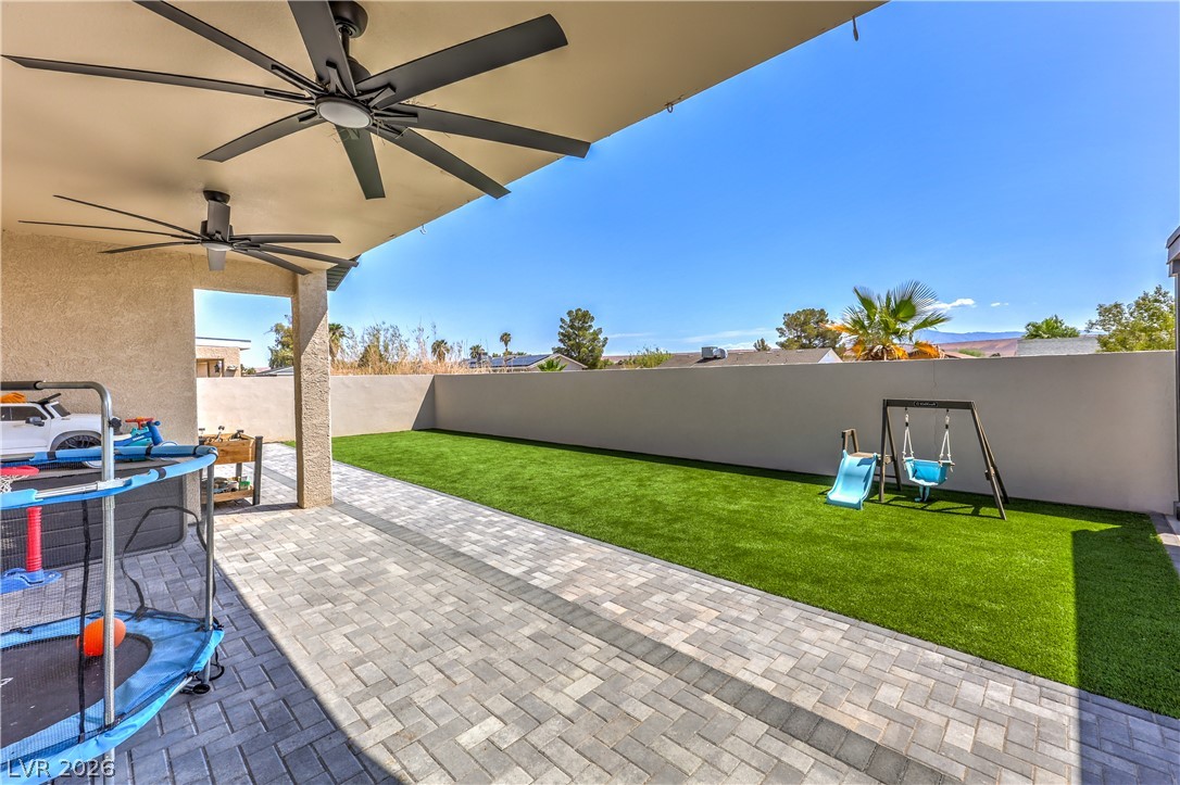 580 Lillian Condie Road Overton, NV 89040 - Photo 30 of 37 An inviting covered patio featuring paver stones extends to a manicured synthetic lawn, ideal for outdoor leisure.