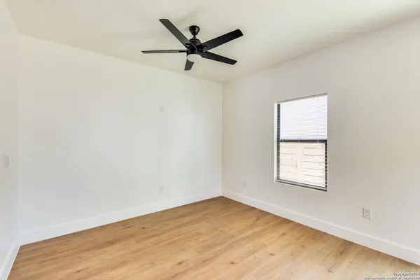 an empty room with a window and a ceiling fan