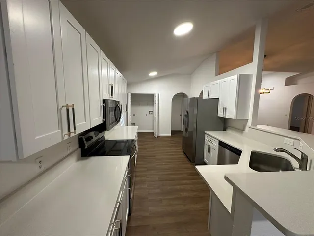 a large white kitchen with a sink and refrigerator