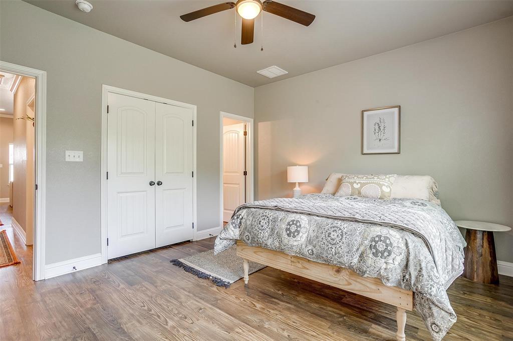 2708 James Road Granbury, TX 76049 - Photo 25 of 34 a spacious bedroom with a bed and a chandelier