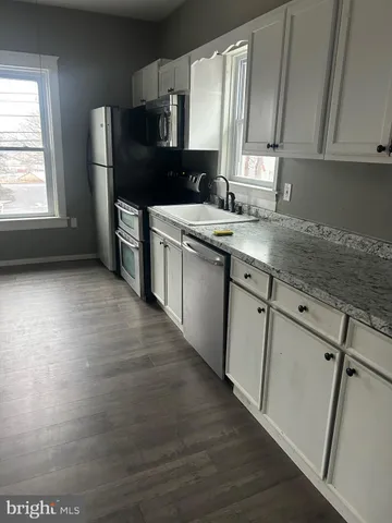 a kitchen with granite countertop a sink cabinets and stainless steel appliances