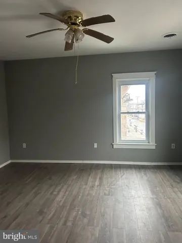 an empty room with wooden floor fan and windows