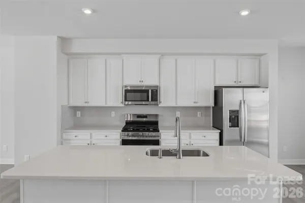 a kitchen with stainless steel appliances a stove a sink a refrigerator and cabinets