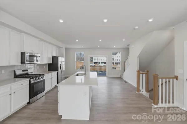 a kitchen with stainless steel appliances kitchen island wooden floors and white cabinets