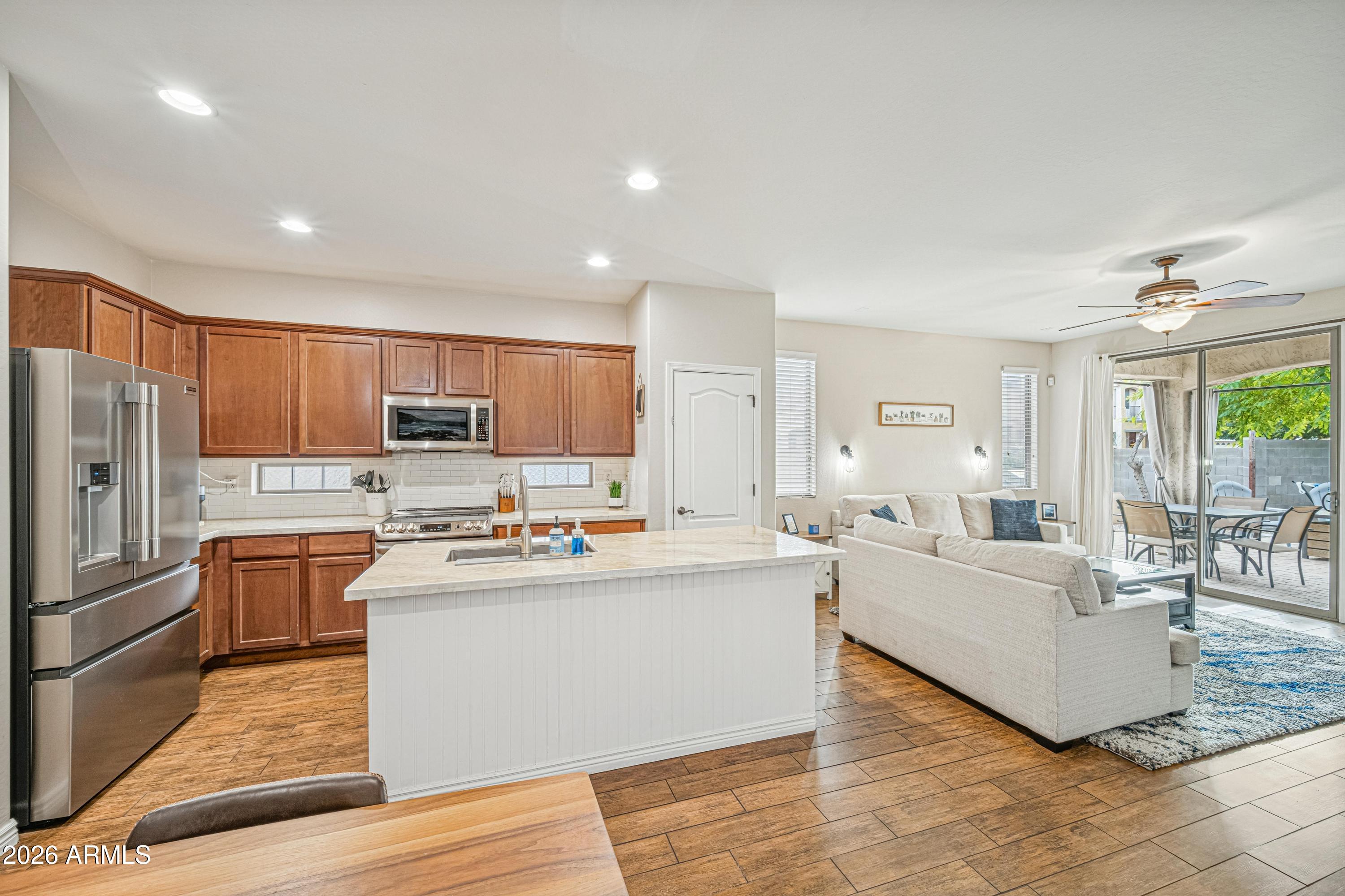 3942 South Mandarin Way Gilbert, AZ 85297 - Photo 5 of 32 a view of a kitchen with kitchen island stainless steel appliances a stove a refrigerator a sink dishwasher a oven with white cabinets and wooden floor