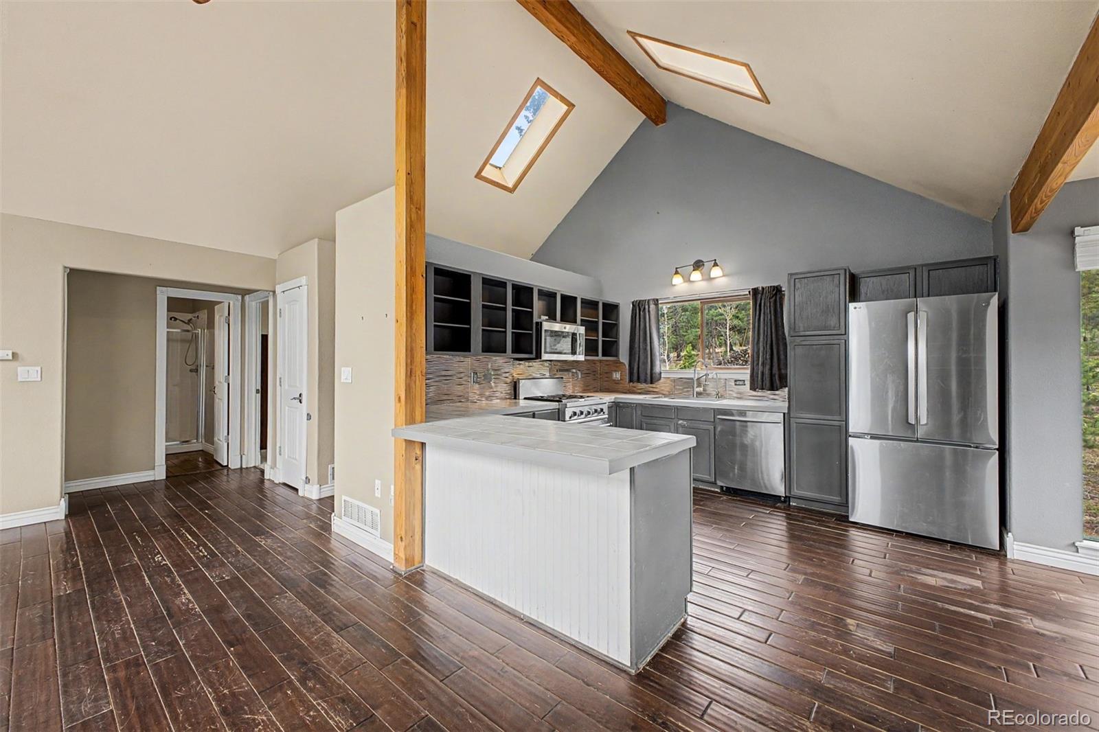 76 Highlands Drive Bailey, CO 80421 - Photo 17 of 49 a kitchen with stainless steel appliances a refrigerator a sink dishwasher a stove with wooden floor and cabinets