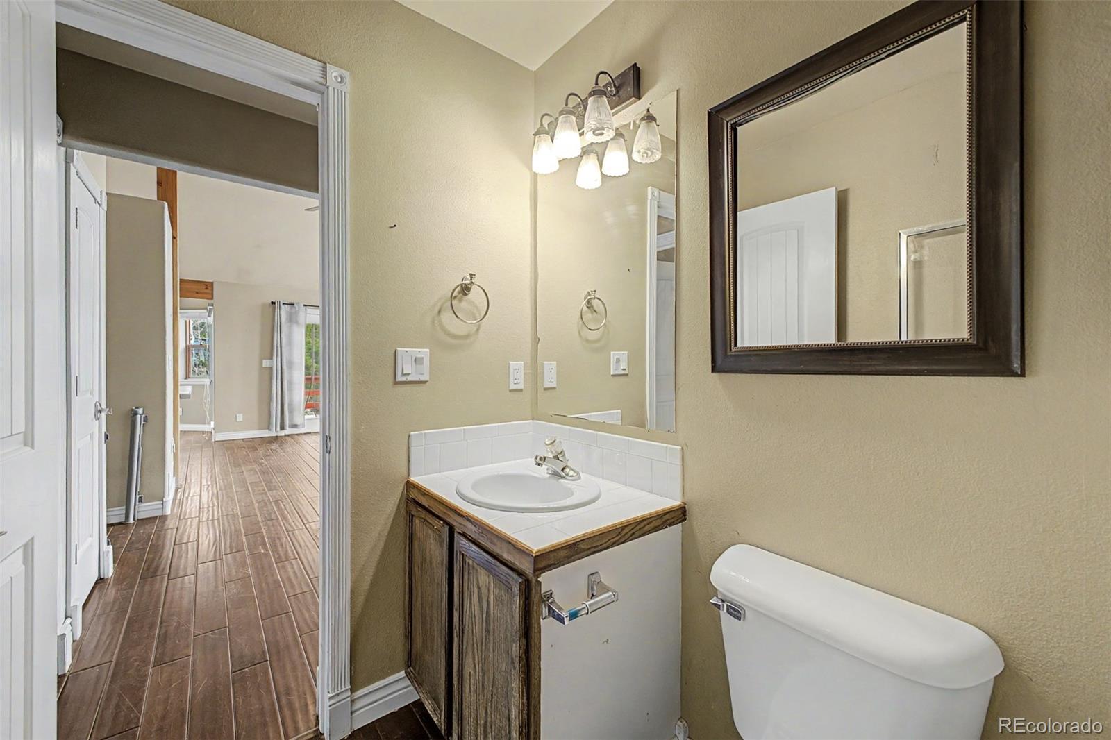 76 Highlands Drive Bailey, CO 80421 - Photo 29 of 49 a bathroom with a granite countertop sink a toilet and a mirror