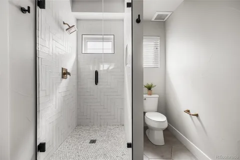 a bathroom with a granite countertop shower a toilet and a shower
