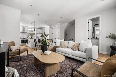 a living room with furniture a rug kitchen and a table