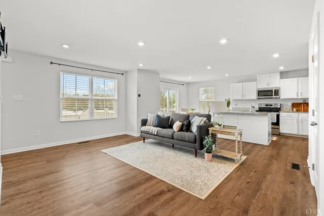 a living room with furniture and kitchen view with wooden floor