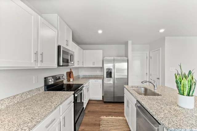 a kitchen with stainless steel appliances granite countertop a sink a stove and a refrigerator