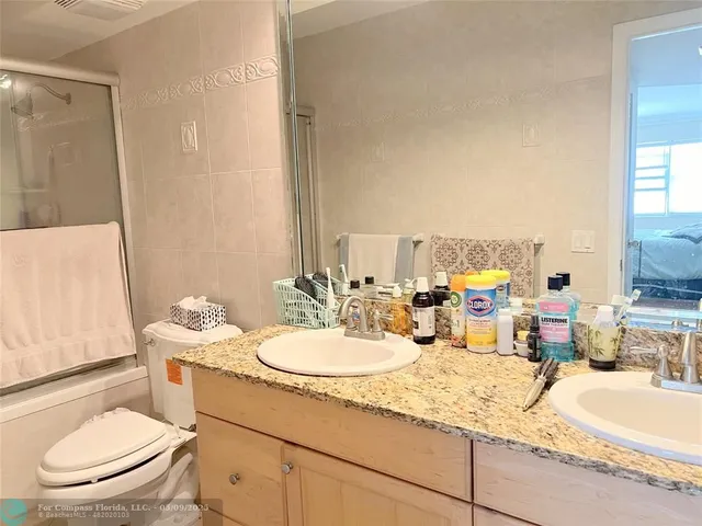 a bathroom with a granite countertop sink mirror vanity and toilet