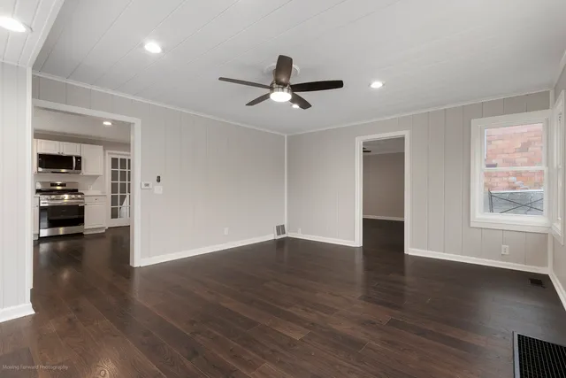 a view of an empty room with window and wooden floor