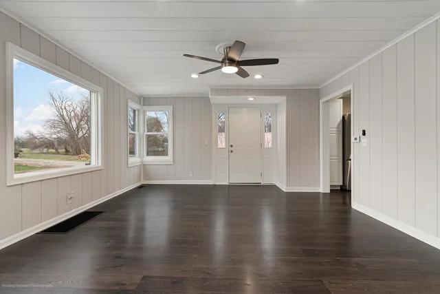 a view of an empty room with wooden floor and a window