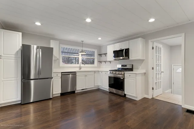 a kitchen with a refrigerator stove and wooden floor